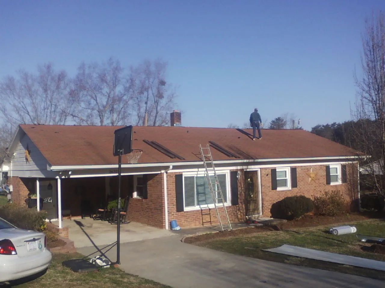 Roofer stripping a shingle roof on a brick ranch before metal panels in Leavenworth