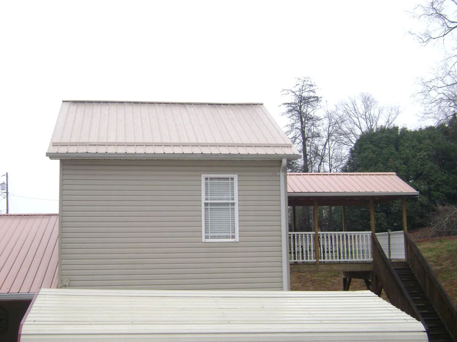 Tan metal roofs on a two story addition and attached porch, from a Roof Replacement job in Leavenworth