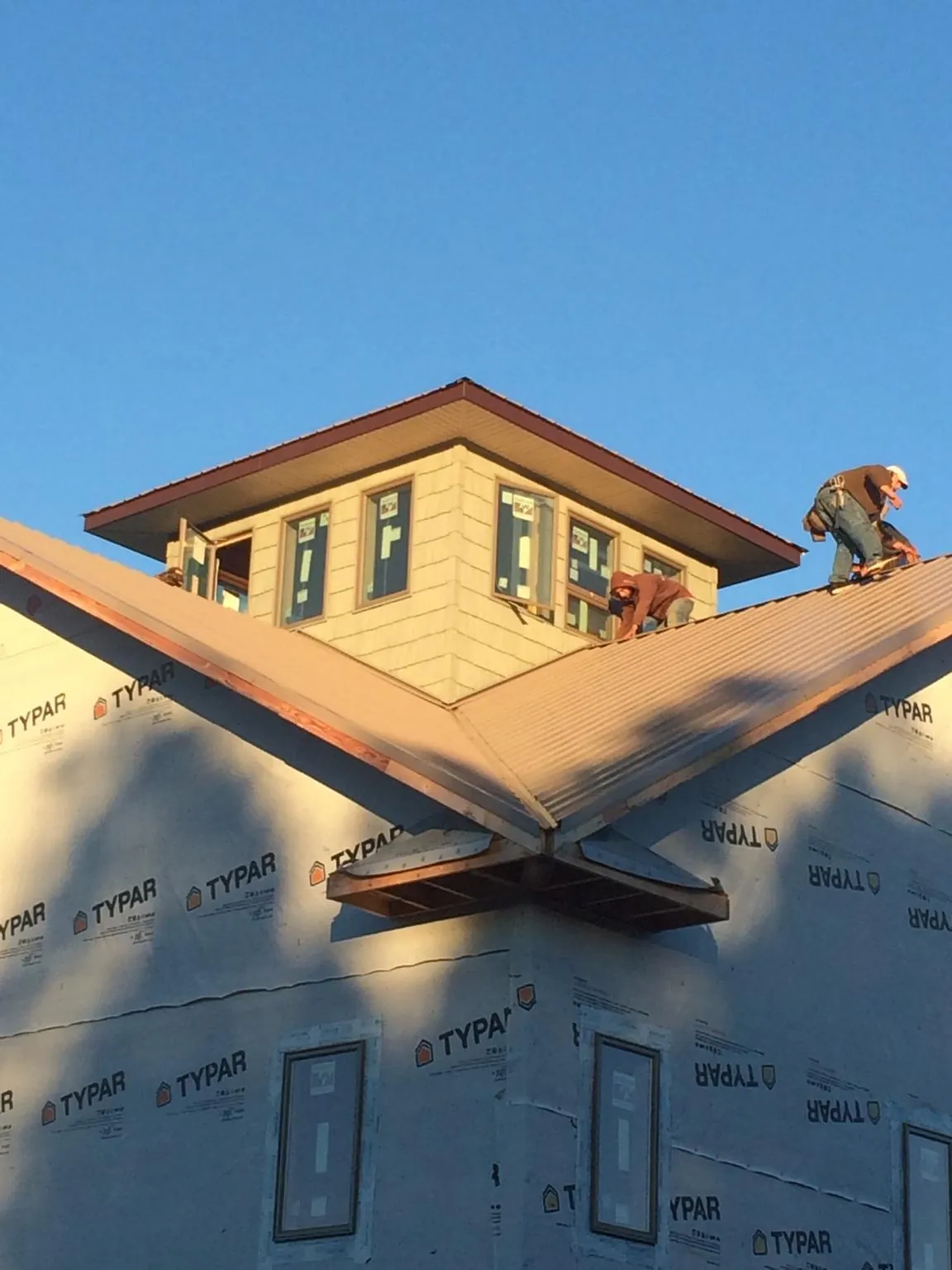 Roofers working around a rooftop cupola on a new metal roof at sunset — Roof Waterproofing in Leavenworth by Roofing Brothers
